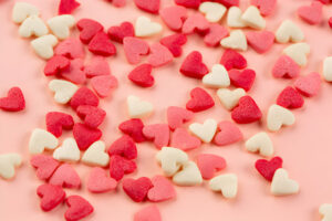 Bonbons en forme de cœur rouges et blancs sur fond rose