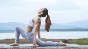 Femme pratiquant le yoga en plein air devant un lac paisible