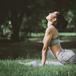 Femme pratiquant la posture du cobra lors d'une séance de yoga dans un parc