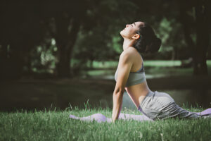 Femme pratiquant la posture du cobra lors d'une séance de yoga dans un parc